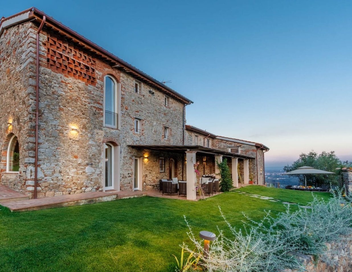 Villa Gioma from outside: the stone farmhouse and the terrace over the hills of Lucca